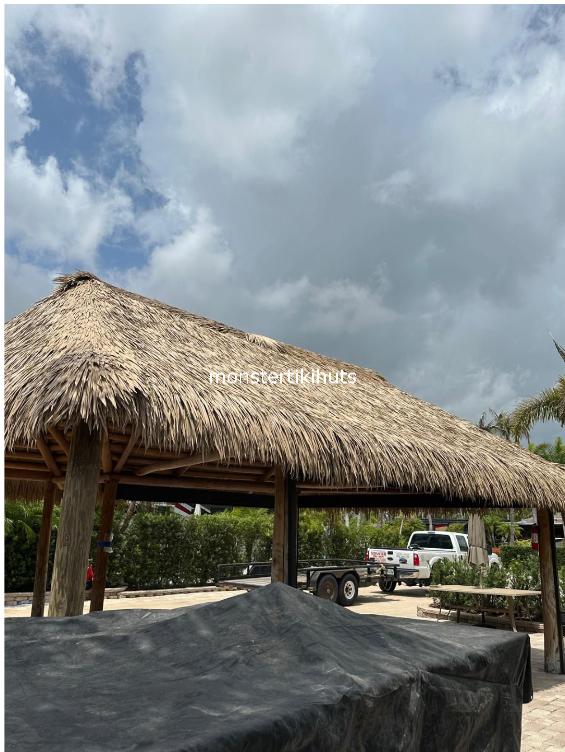 Large tiki hut with synthetic thatch roof and cloudy sky